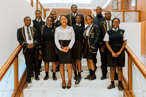 Firm Foundation learners in school uniform gathered on the hotel staircase