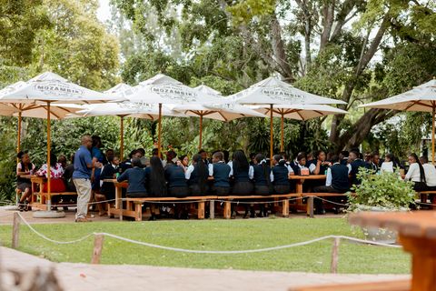 Uniformed learners seated together outdoors on an off-campus restaurant outing