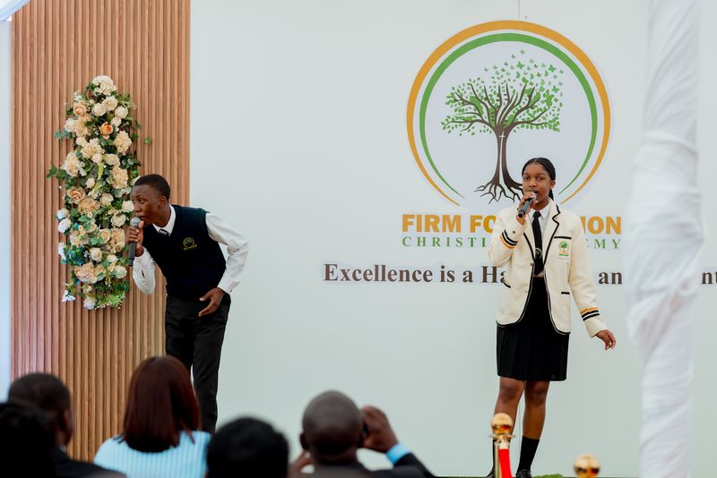 Learners performing in front of the Firm Foundation backdrop at prize giving