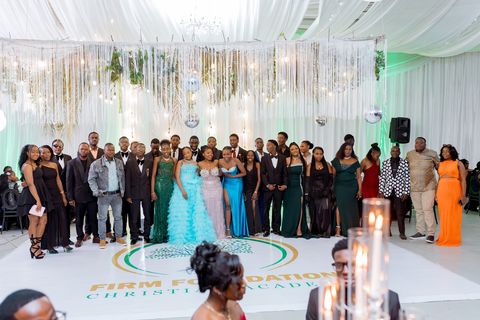 Prom guests gathered around the floor bearing the Firm Foundation school logo