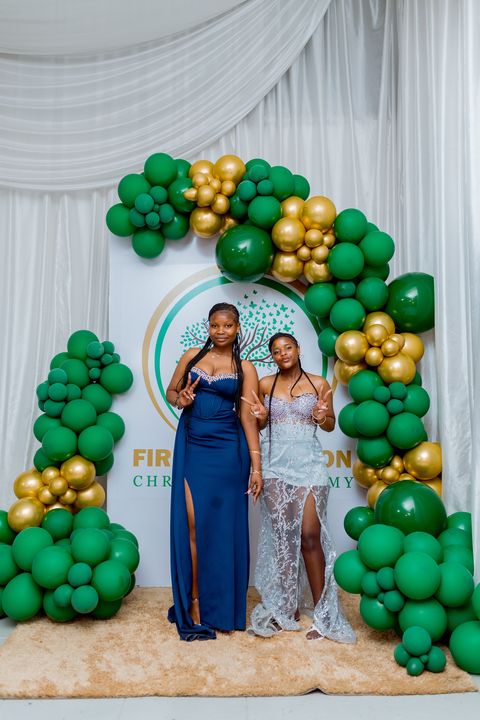 Prom friends together beside the branded school backdrop
